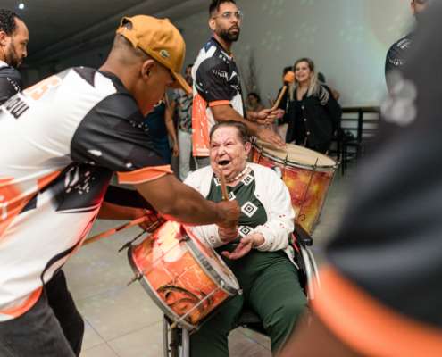 Dona Helena participando e tocando um instrumento em sua Festa de Aniversário